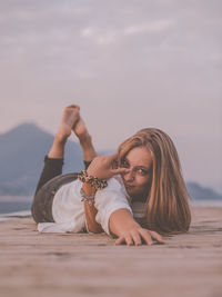 Portrait of woman lying on beach against sky