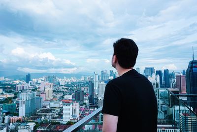 Rear view of man standing in city against sky