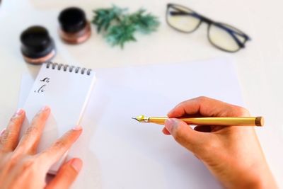 Calligraphy expert holding fountain pen over paper on table