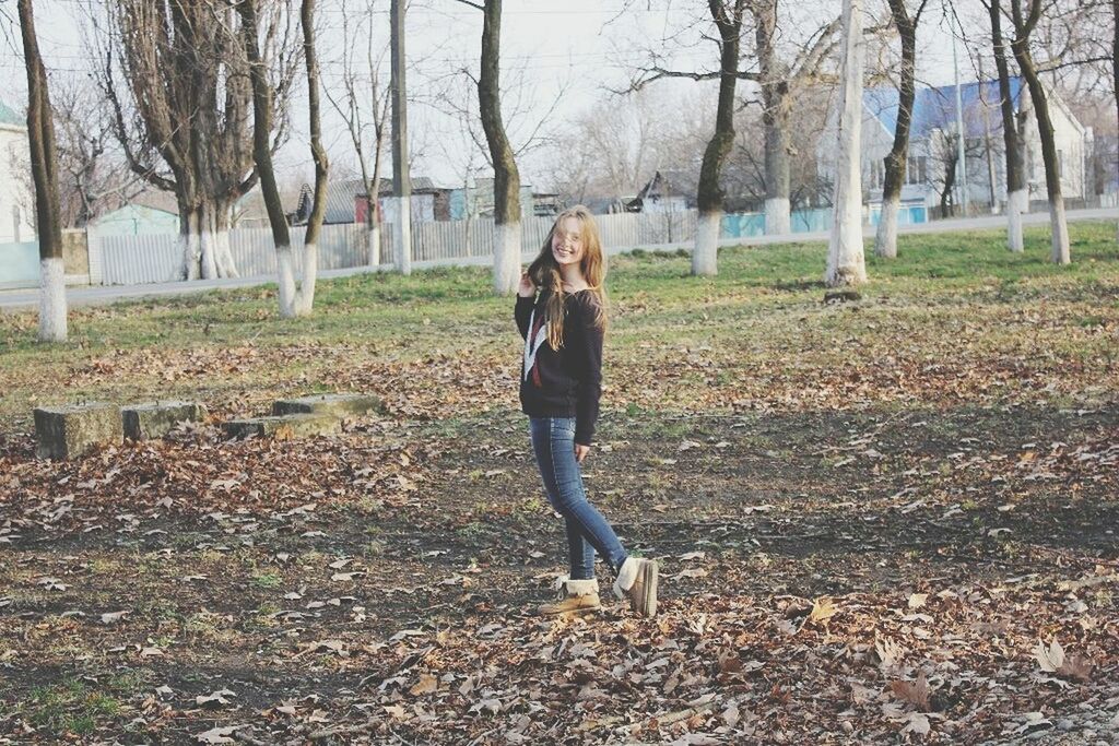 full length, tree, lifestyles, casual clothing, leisure activity, young adult, standing, bare tree, person, tree trunk, front view, young women, day, field, autumn, nature, rear view, outdoors