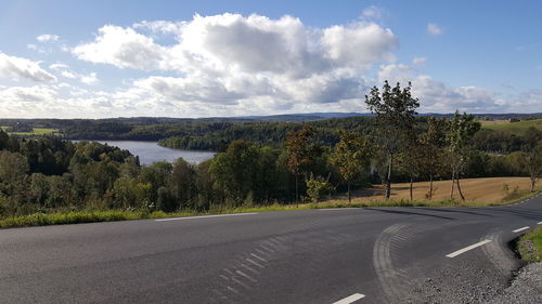 Scenic view of road by trees against sky