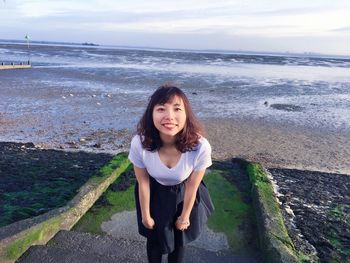 Portrait of smiling woman standing on steps at beach