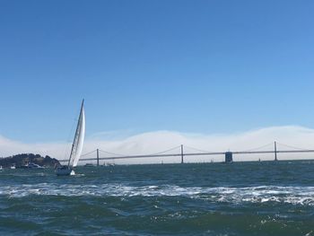 View of suspension bridge over sea against clear sky