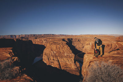 A man with a dog is standing near horseshoe bend, arizona