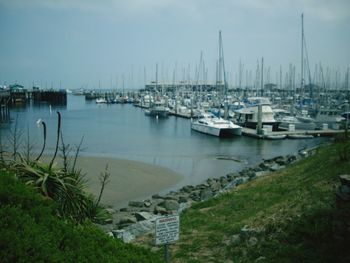 Boats moored at harbor against sky