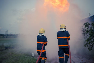 Firefighters spraying water while standing on field 