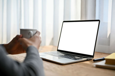 Cropped hand using laptop at table