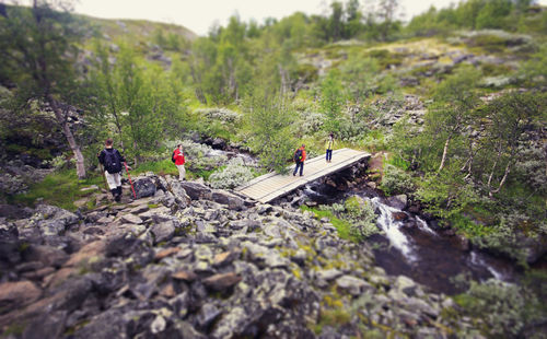 Hikers walking on footbridge on rocky field