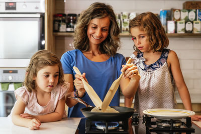 Mother and daughters preparing food in kitchen at home