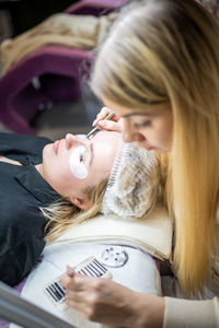 Woman applying medical eye patch to customer in salon