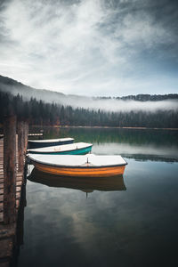 Boat moored in lake against sky