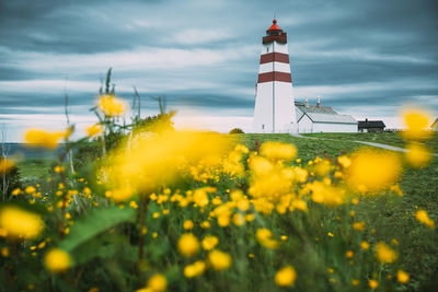 Lighthouse by sea against sky