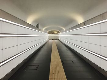 Empty illuminated tunnel with building in background