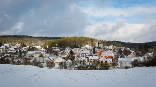 Houses on field by building against sky