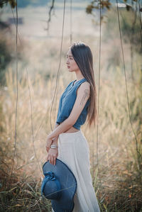 Side view of young woman standing against sky