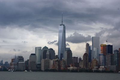 City at waterfront against cloudy sky