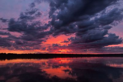 Scenic view of lake against dramatic sky during sunset