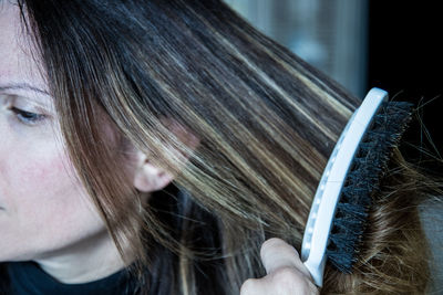 Close-up of young woman brushing hair