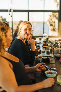 Portrait of smiling woman with hand on chin sitting by friends at retreat center