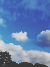 Low angle view of silhouette trees against blue sky
