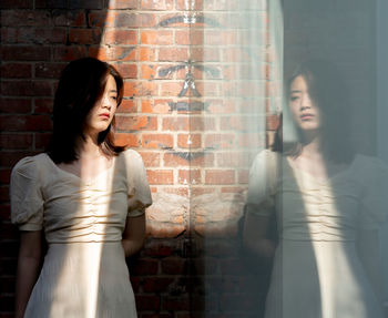 Young woman standing against wall