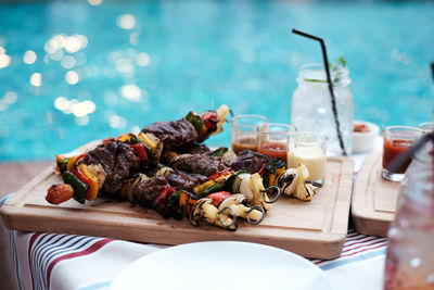 High angle view of barbecued meat and vegetables in skewers on tray at pool party