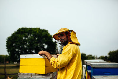 Beekeeper working over beehive at farm