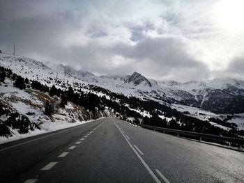 Road leading towards snowcapped mountains against sky