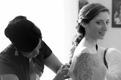 Mother helping bride with wedding dress