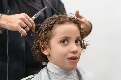 Midsection of barber cutting boy hair at salon