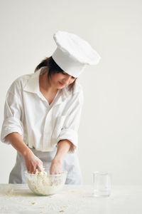Woman kneading dough against white background