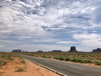 Road amidst field against sky