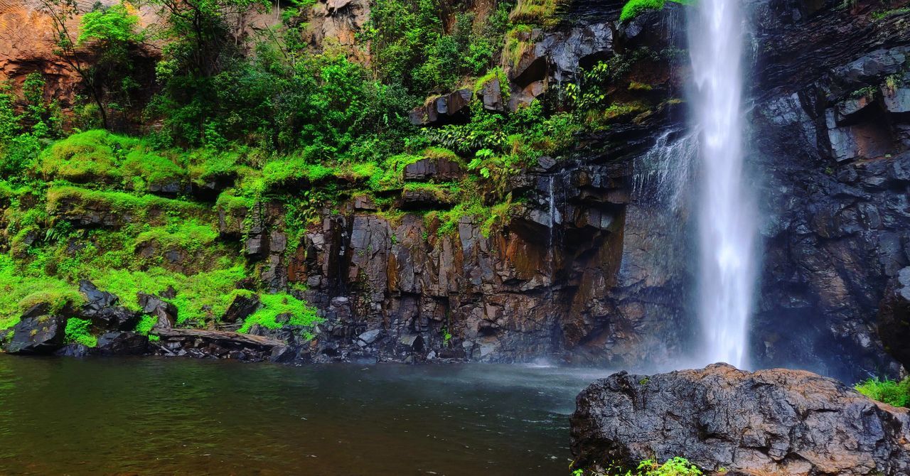 SCENIC VIEW OF WATERFALL AGAINST ROCKS