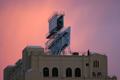 Low angle view of billboard on building against sky during sunset