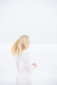 Side view of woman standing in sea against sky