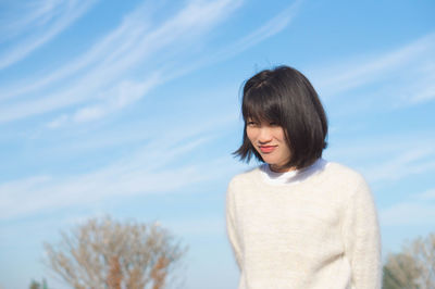 Low angle view of smiling woman standing against sky