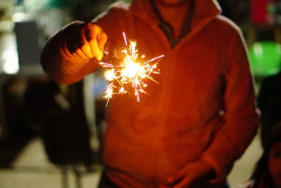 Close-up of man holding sparkler at night