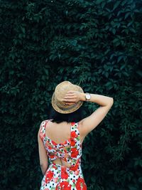 Young woman standing against plants