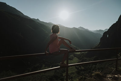 Mid adult woman looking at view while sitting on railing