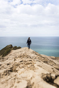 Rear view of man on beach against sky