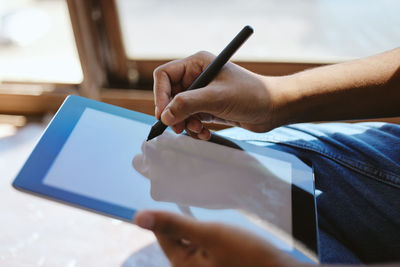 Midsection of man using digital tablet