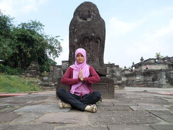 Portrait of senior man sitting on temple against sky