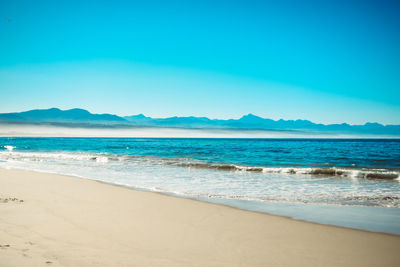 Scenic view of beach against clear blue sky