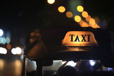Close-up of illuminated taxi sign on street at night