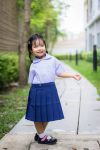 Portrait of schoolgirl standing on footpath