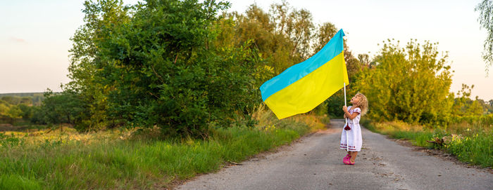 Rear view of woman holding flag against sky