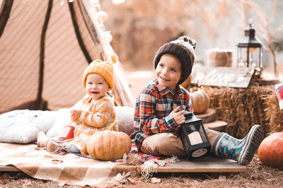 Happy children wearing autumn clothes posing with pumpkins over lights outdoors. fall season.