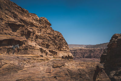 Rock formations on landscape against clear blue sky