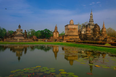 Pond by wat mahathat temple against sky