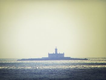 Lighthouse in sea against clear sky